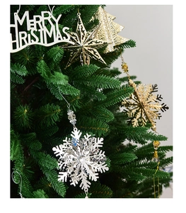 Close-up of metal snowflake, star and Merry Christmas ornaments on a green Christmas tree