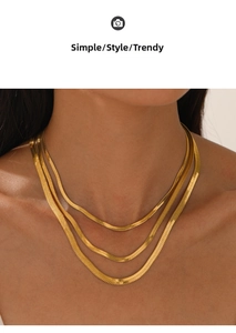 Detailed close-up of triple-layered golden flat snake chain necklaces on a female model