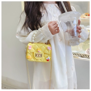 Cute yellow mini child handbag with pearl handle and cartoon charms shown with a girl