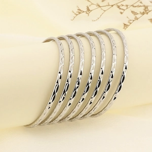 Detail of 7pcs stacked silver bangles with diamond-cut diamond pattern on a display stand