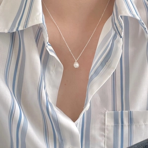 Close-up of minimalist sterling silver necklace with white pearl on a model's collarbone