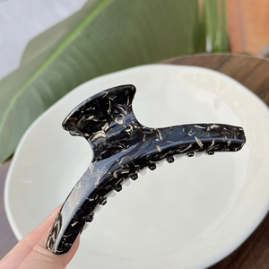 Detail of large acetate hair claw clip with elegant black and beige marble texture