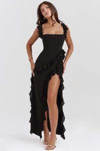 Dettaglio dell'abito nero con spalline a balze e spacco alto per un look sofisticato