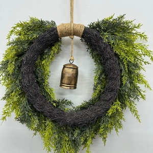 Close-up of heart wreath with cedar leaves, rustic bronze bell and natural jute rope
