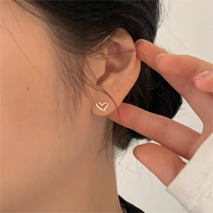 Close-up of minimalist silver heart stud earrings worn on the ear for style view