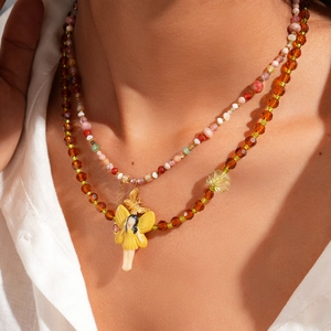Detail of double-layer beaded necklace featuring amber crystals and yellow fairy pendant
