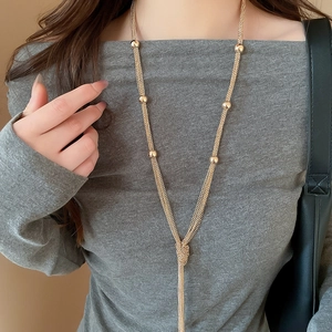 Close-up of golden multi-layer knotted tassel necklace with metallic bead details