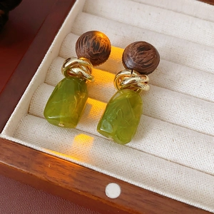 Close-up of vintage geometric earrings with brown wood beads and green resin drops
