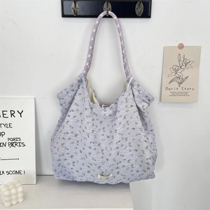Détail du sac fourre-tout à fleurs avec poignées en corde colorée sur crochet mural