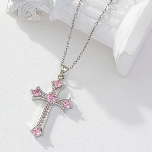 Close-up of a silver cross pendant with a pink zircon stone and pearl chain detail