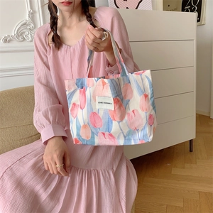 Sac à main en toile à fleurs porté par un mannequin en robe plissée rose