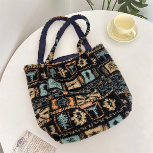 Detail of plush tote bag showing abstract color patchwork and brand leather label