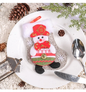 Detailed view of snowman cutlery holder sock with golden bell on festive plate