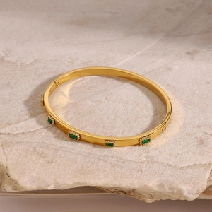 Gold stainless steel oval bracelet with four rectangular green zircons on a stone