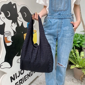 Detail of black bubble texture on large canvas tote bag worn by model in street setting