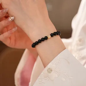 Chic black obsidian beaded bracelet with yellow crystal accent on female wrist