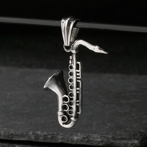 Macro shot of a detailed saxophone pendant made of polished stainless steel on a dark stone
