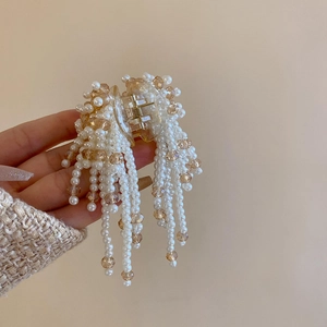 Detail of elegant faux pearl and amber crystal tassel hair claw clip with resin base