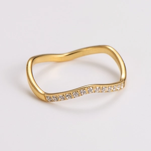 Detail of a wavy gold stainless steel ring featuring shimmering cubic zirconia stones