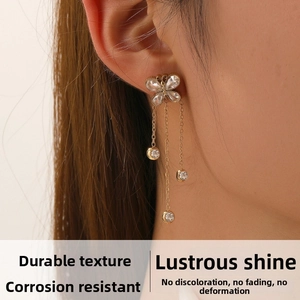 Gros plan sur les boucles d'oreilles papillon dorées avec pompons et zircons brillants
