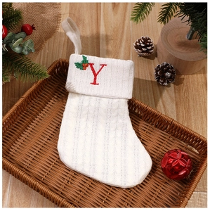 Detailed knit of white Christmas stocking with red letter Y and holly embroidery