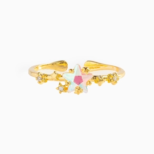 Macro detail of adjustable gold ring featuring iridescent star stone and zircon inlays