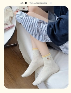Detail of soft cream crew socks featuring cute puppy embroidery and colorful flecks