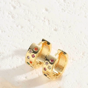 Close-up of golden hoop earrings featuring inlaid colorful cubic zirconia on white stone