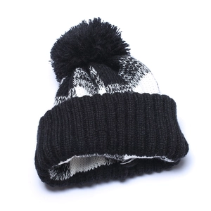 Winter knit beanie with black and white plaid pattern and large faux fur pom-pom topper