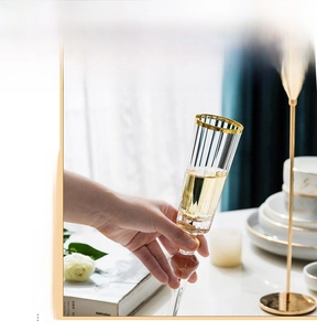 Detail of crystal champagne glass with gold rim and beaded stem in elegant setting