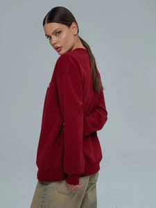 Λεπτομερής πλαϊνή όψη από σκούρο κόκκινο oversized φούτερ με βαμβακερή υφή και άνετη γραμμή