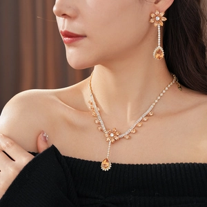 Close-up of golden floral jewelry set with amber zircon pendant on model