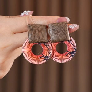 Macro detail of retro earrings with wood-texture square and bamboo print pattern