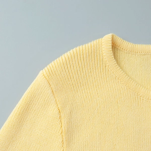 Close-up of bright yellow ribbed knit texture and stitching details on a long sleeve set