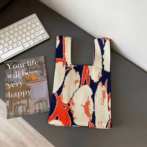 Close-up of knit tote bag with blue and orange floral pattern on a grey desktop