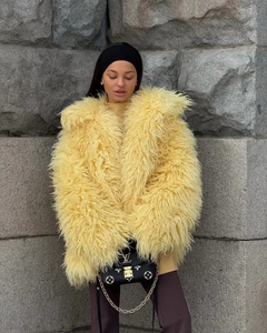 Close-up of the plush faux fur texture and vibrant yellow material of the oversized coat