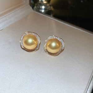 Détail de boucles d'oreilles fleur en perle dorée avec cristaux dans un écrin beige