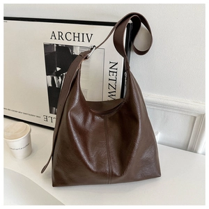Detail of dark brown leather tote bag with vertical stitching and wide shoulder strap