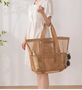Khaki-Strandtasche aus Mesh mit vielen Taschen, Sonnenbrille und Hautpflegeprodukten im Detail