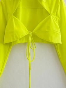 Détail d'un chemisier court jaune fluo avec nœud frontal et col à revers de style urbain