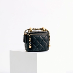 Detailed macro view of black quilted sheepskin bag with gold chain and ball adjustment
