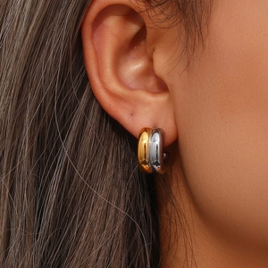 Close-up of dual-tone gold and silver curved double C-shaped stud earrings on model