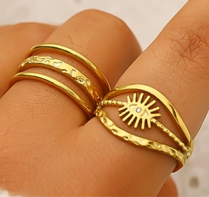 Detail of 18K gold-plated stacking rings with hammered texture and sun eye design