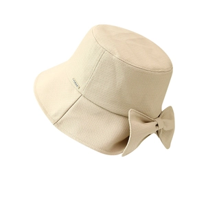 Beige woven bucket hat for women with a side bow and metal logo on a clean white background
