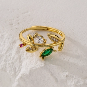 Gold leaf ring with colorful marquise zircons on white stone texture, elegant open band
