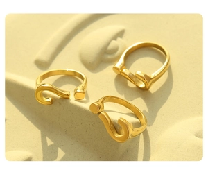 Three gold question mark adjustable rings on light yellow embossed textured background