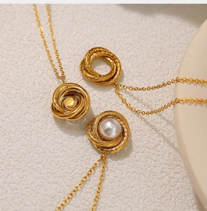Detailed top view of 18K gold plated twisted necklace with pearl pendant on beige surface