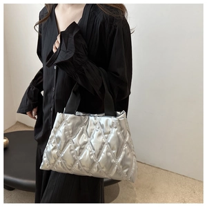 Close-up of a silver quilted tote bag with metallic finish and black ribbon handles
