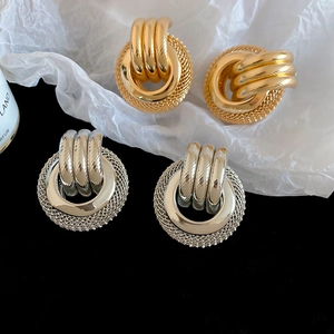 Détail de boucles d'oreilles rondes dorées et argentées avec texture en maille torsadée