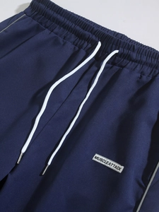 Detail of navy blue woven joggers featuring elastic waist and white drawstring closure